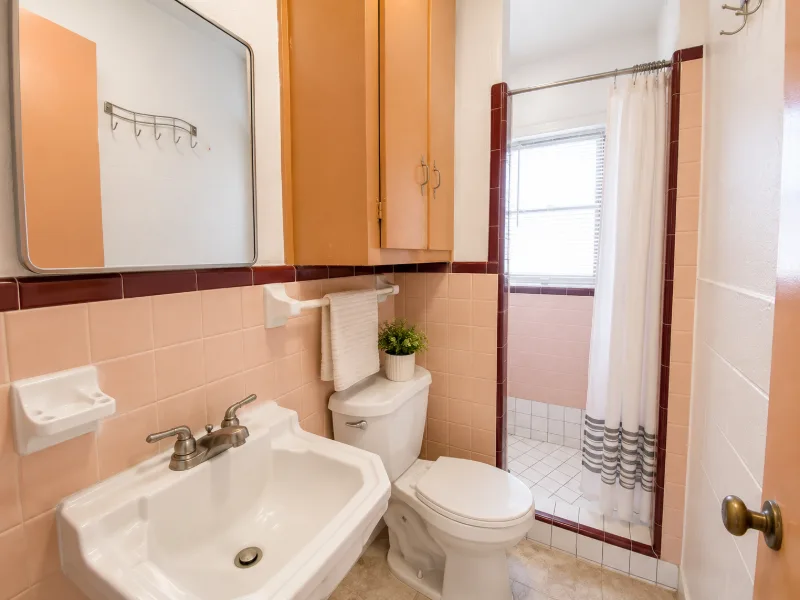 Bathroom with pink tile and a window over the tub