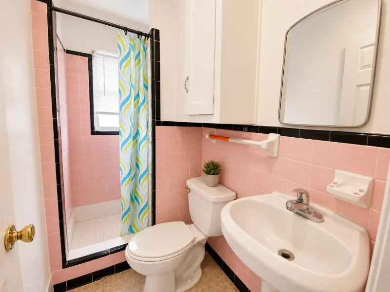 Bathroom with pink tile and a patterned shower curtain