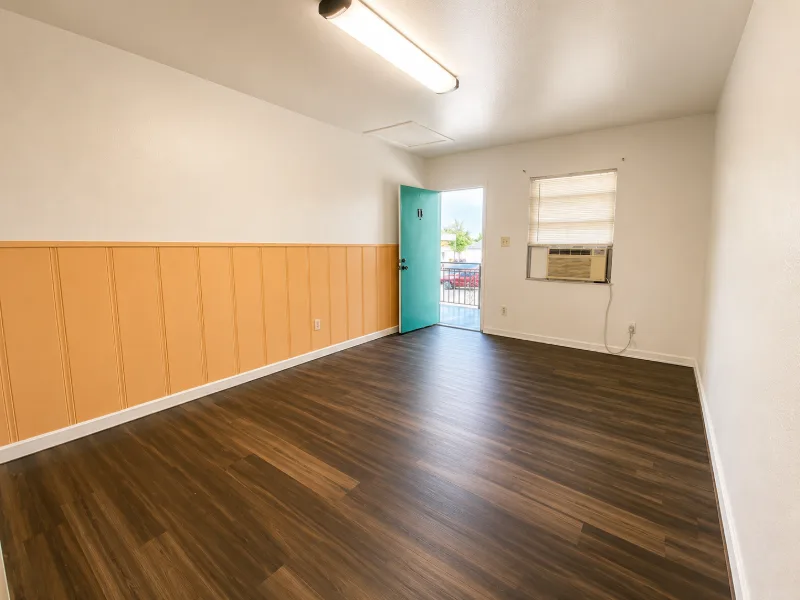 Efficiency main room with dark wood floor and wainscoting, front door open